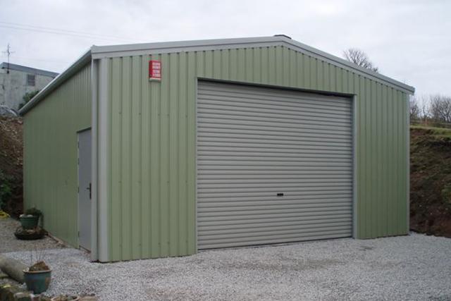 A green building with a roller door and personal access door at the side